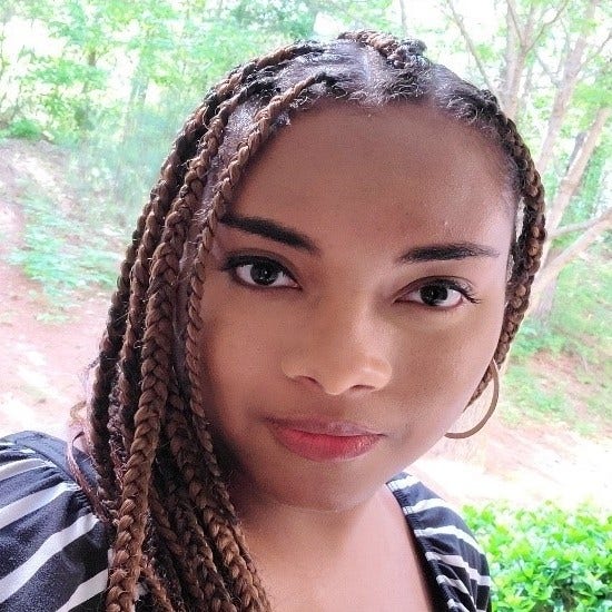 young Black woman with long braids, striped top, hoop earring 