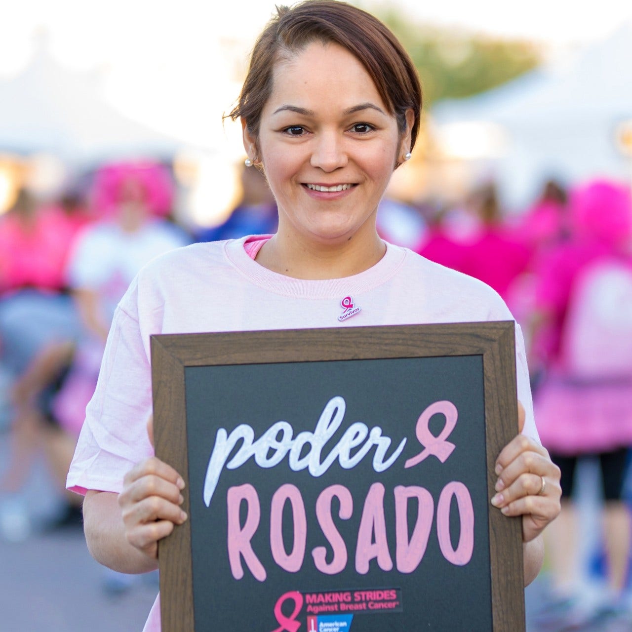 hispanic woman holding chalkboard sign at Making Strides Against Breast Cancer Event
