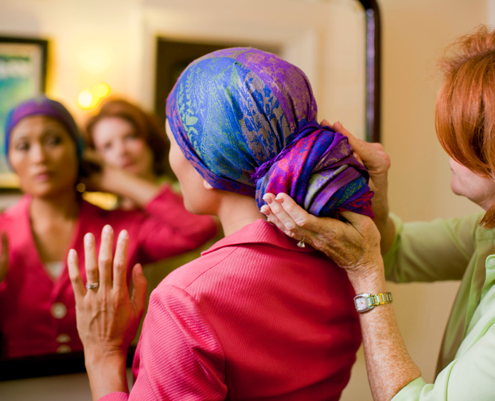 a woman helps a cancer patient with her head scarf