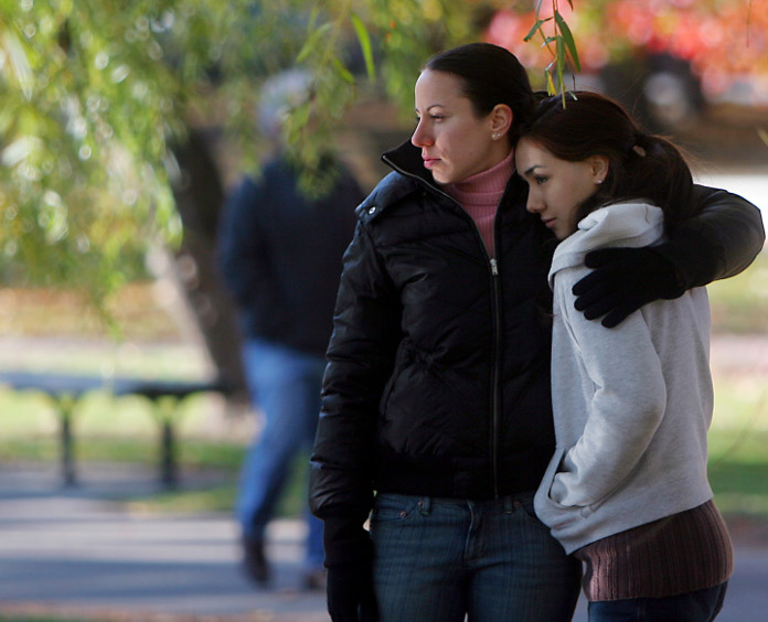 two young girls in jackets and glovesr embrace outside  