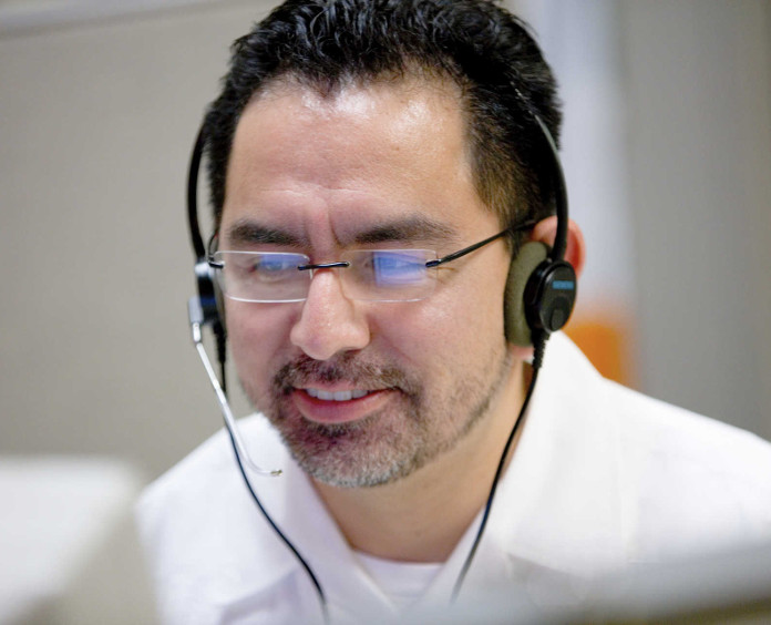 A man with glasses wearing headphones looks at his computer