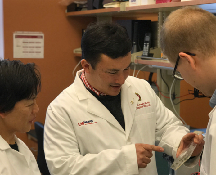 Randy Kimple, MD, PhD, Kwang Nickel, PhD, a research specialist in Kimple’s lab, and Austin Maas, BS, a former research intern look at cell survival assays. These assays show cancer cells (the control) compared with cancer cells treated with cetuximab, cancer cells treated with an autophagy inhibitor, and cancer cells treated with both cetuximab and the autophagy inhibitor. 