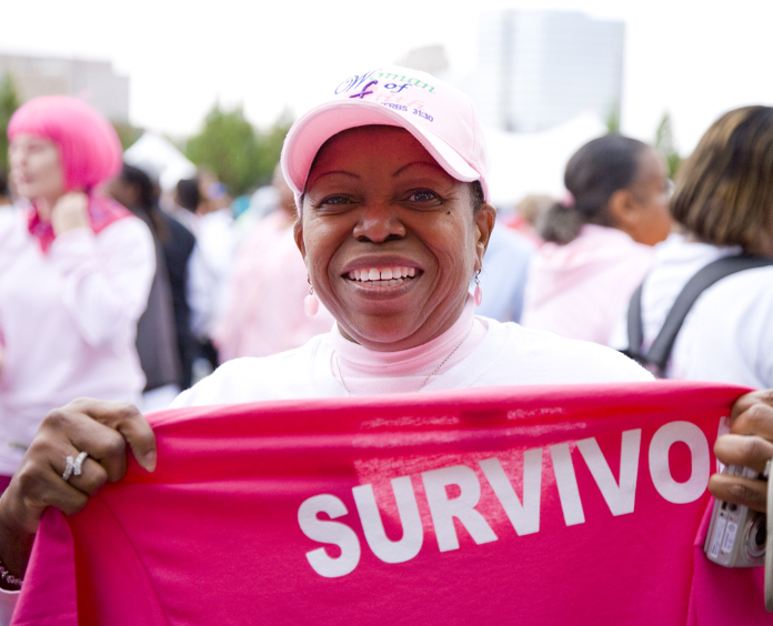 woman holding a survivor tee shirt at outdoor event